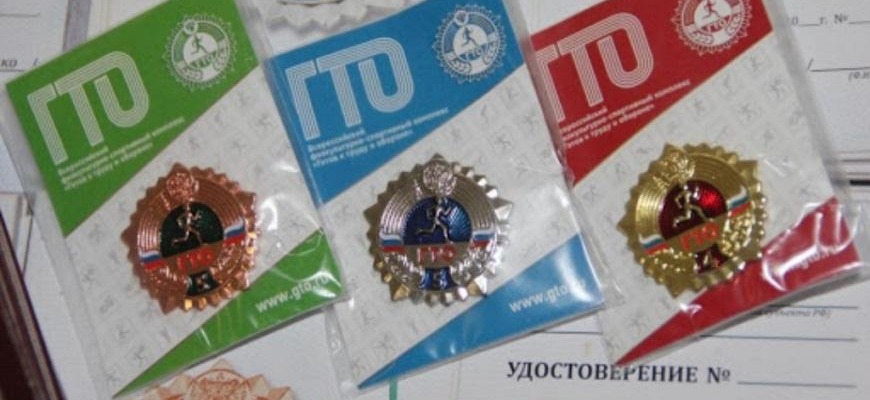 Бронзовый, серебряный и золотой знаки отличия ГТО рядом с бланком удостоверения